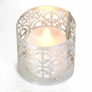 Macro view of silver laser-cut metal candle sleeve with hollow floral pattern and LED light
