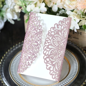 Close-up of pink glitter laser-cut floral invitation card with intricate lace details