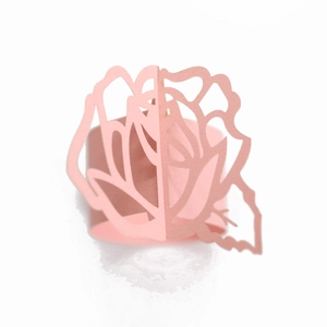 Detail of pink laser-cut paper napkin ring featuring a 3D rose and leaf hollow design