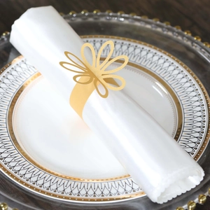 Close-up of golden petal napkin ring with laser-cut design on a white satin napkin
