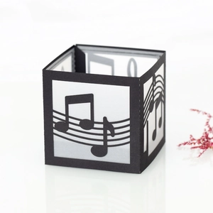 Detail of laser-cut musical notes on a square black paper lantern with a staff pattern