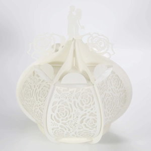 Macro shot of white laser-cut wedding favor box with rose patterns and couple silhouette