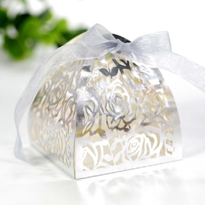 Detail of silver laser-cut floral wedding favor box with an elegant ribbon bow tie