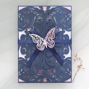 Detail of laser-cut navy blue wedding invitation with ribbon and rose gold butterfly