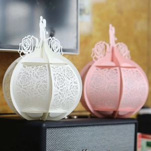 Detail of 3D laser-cut paper wedding gift boxes with hollow rose patterns and silhouettes