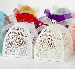 Detail of laser-cut rose hollow favor boxes with silk bows in various vibrant colors