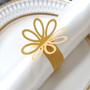 Detail of elegant gold hollow flower napkin ring on a white napkin for wedding decor