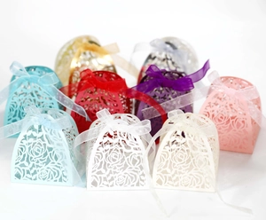 Detail of laser-cut rose hollow favor boxes with elegant sheer organza ribbon ties