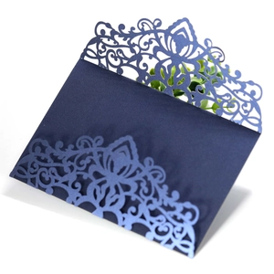 Detail of navy blue laser cut invitation sleeve with intricate floral vine patterns