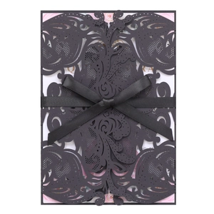 Macro detail of laser-cut floral patterns and black satin ribbon on formal invitation