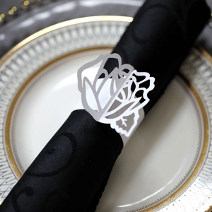 Detail of laser-cut white rose paper napkin ring on black silk napkin with gold-rimmed plate