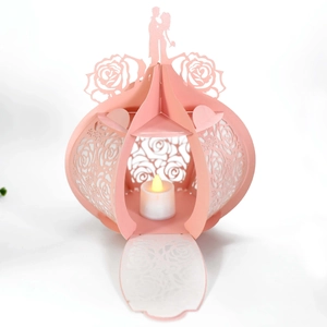 Detail of pink paper lantern with hollow rose patterns and glowing LED candle