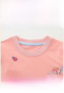 Détail d'une robe rose en coton pour fille avec col rond et broderie florale délicate