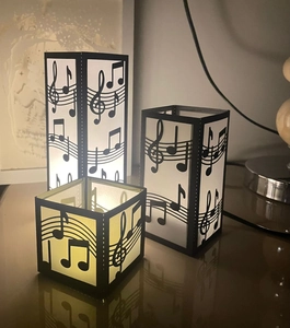 Detailed view of three black music note paper lanterns with laser-cut musical staff designs