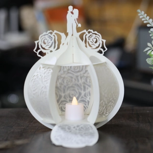 Detail of white laser-cut pumpkin carriage paper lantern with wedding silhouette and LED