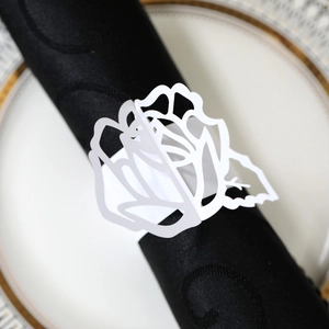 Close-up of laser-cut white pearl paper napkin ring with 3D rose flower design