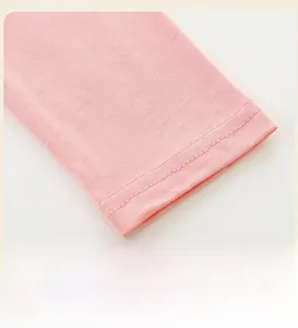 Détail du poignet en coton rose tricoté montrant la double couture et la texture du tissu