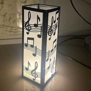 Detail view of the laser-cut musical note pattern on a warm LED square table lamp