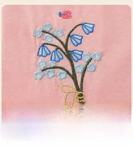 Gros plan de broderies florales avec fleurs bleues et papillons sur tissu en maille rose