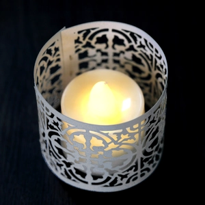 Macro shot of laser-cut white filigree candle holder with warm LED light glow