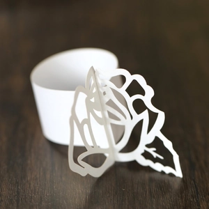 Macro detail of laser-cut white paper napkin ring with hollow rose flower pattern