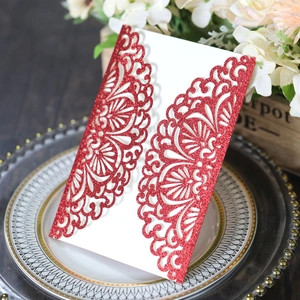 Detail of red glitter laser-cut wedding invitation with intricate floral scroll pattern
