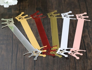 Detailed view of crown shaped pearlescent paper napkin rings in six metallic colors