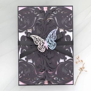 Macro view of laser-cut black invitation with ribbon and 3D gradient butterfly card