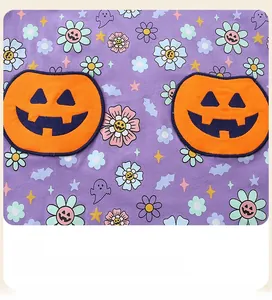 Détail d'imprimé fantôme sur tricot violet avec des écussons de citrouille en relief