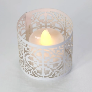 Detailed macro view of laser-cut scroll pattern paper lampshade with warm LED candle light