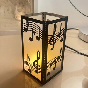 Detailed laser-cut musical notes and staff pattern on black paper tea light candle holder