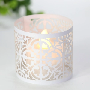 Macro shot of white laser-cut hollow candle sleeve with warm yellow LED lighting