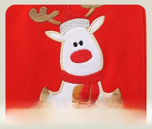 Détail de la broderie renne avec bonnet de Noël et écharpe sur tissu rouge