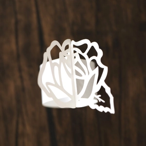 Macro shot of laser-cut white pearl paper napkin ring in detailed rose flower design