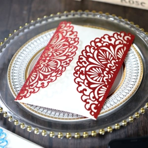 Close-up of red glitter laser-cut lace wedding invitation with intricate floral details