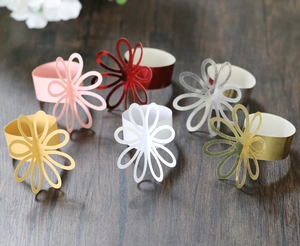 Detail view of hollow flower napkin rings in assorted colors on a rustic wooden background