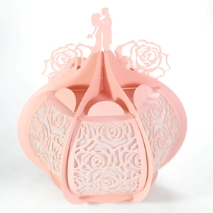 Close-up of pink laser-cut paper gift box with rose hollows and couple silhouette