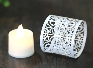 Close-up of white laser-cut floral paper lantern shade with warm LED candle light