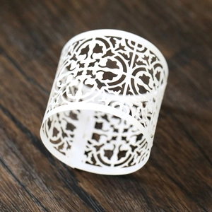 Macro detail of laser-cut white paper napkin ring with intricate floral patterns