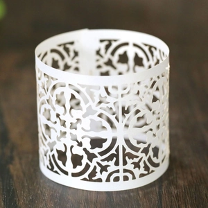 Macro view of white laser-cut hollow pattern paper cupcake wrapper on a wooden table