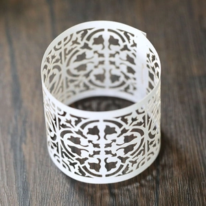 Detail of white laser-cut paper napkin rings with elegant floral hollow pattern