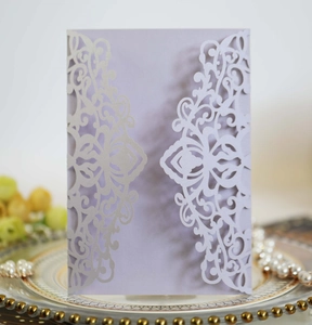 Close-up of laser-cut lavender wedding invitation with pearlescent hollow floral pattern