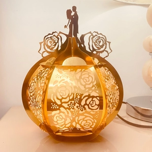 Detailed view of golden hollow pumpkin light with rose patterns and couple silhouette