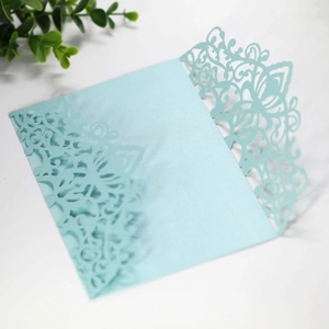 Detail of laser-cut light blue invitation cover with intricate floral lace texture