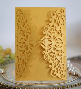 Close-up of golden laser-cut wedding invitation featuring intricate floral vine patterns