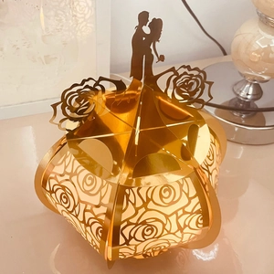 Close-up of golden hollowed-out rose pattern and couple silhouette on wedding favor box