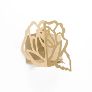 Detail of laser-cut gold paper napkin ring with an intricate rose flower pattern