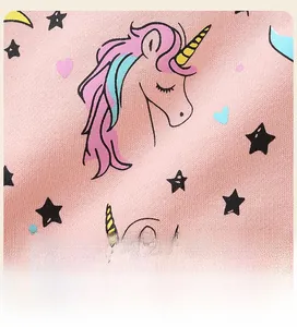 Detailed close-up of pink cotton fabric featuring cute unicorn and star printed patterns
