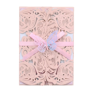 Elegant laser-cut floral wedding invitation in soft pink with ribbon and butterfly