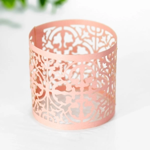 Detail of peach laser-cut paper napkin ring with intricate floral lace pattern
